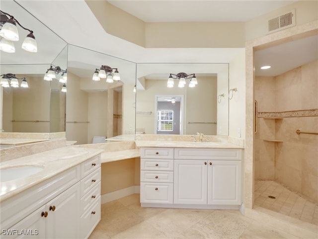 bathroom with visible vents, two vanities, a sink, and tiled shower