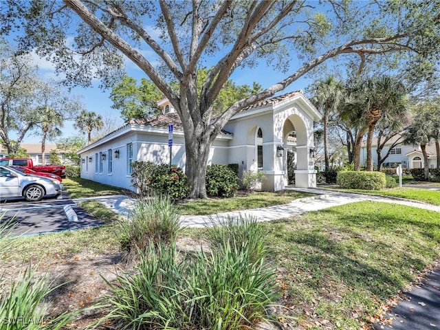 mediterranean / spanish house featuring a front lawn and stucco siding