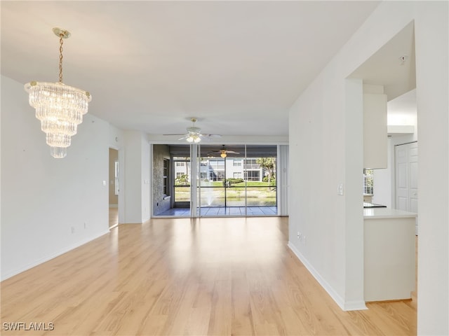 interior space featuring light wood-style floors, baseboards, and ceiling fan with notable chandelier