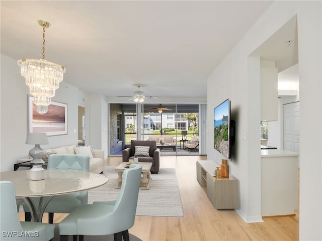 dining space featuring ceiling fan with notable chandelier and light wood-style flooring