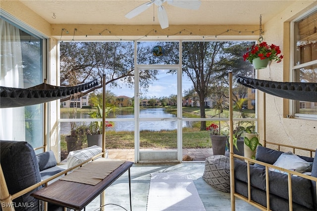 sunroom with a water view, wood finished floors, and ceiling fan