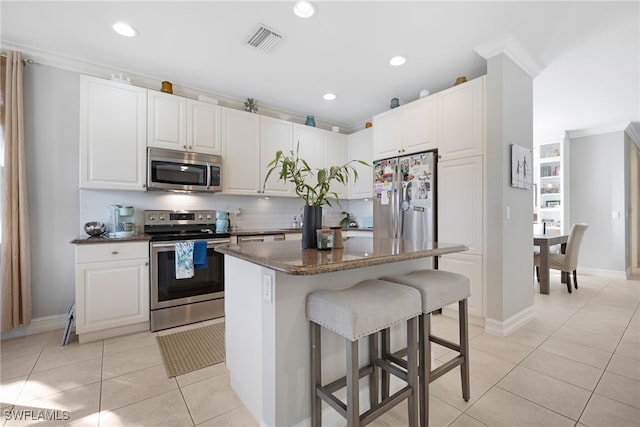 kitchen featuring a breakfast bar, visible vents, decorative backsplash, a kitchen island, and appliances with stainless steel finishes