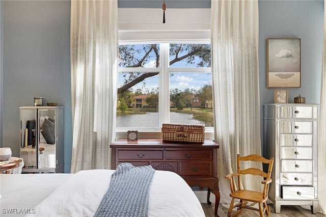 bedroom featuring a water view and wood finished floors