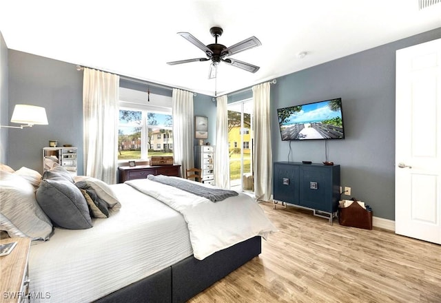 bedroom featuring wood finished floors, a ceiling fan, visible vents, baseboards, and access to outside