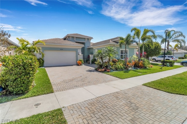 28589 Wharton Dr, Bonita Springs, FL 34135 - view of front facade featuring a garage, a tiled roof, decorative driveway, stucco siding, and a front yard