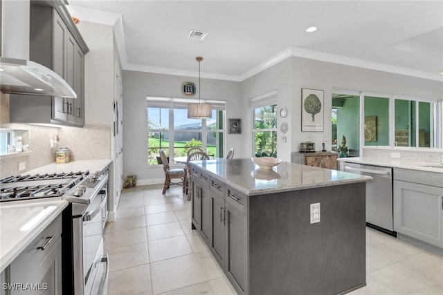 28589 Wharton Dr, Bonita Springs, FL 34135 - kitchen with a center island, crown molding, stainless steel appliances, gray cabinetry, and wall chimney exhaust hood