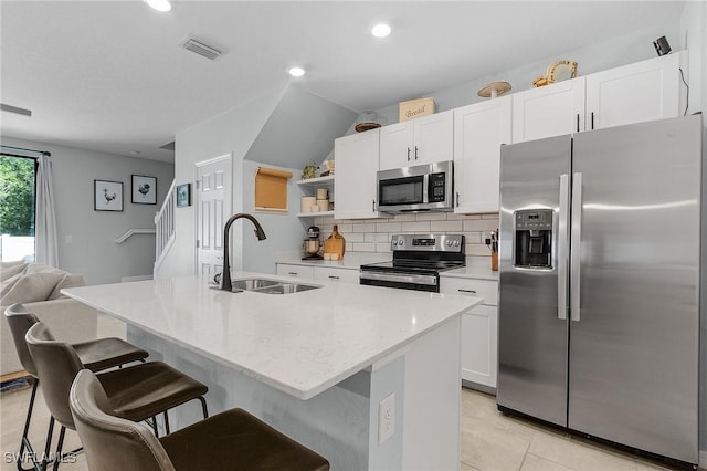 kitchen featuring decorative backsplash, white cabinetry, stainless steel appliances, and a sink