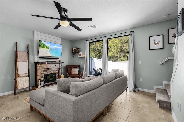 living area featuring visible vents, a fireplace, baseboards, ceiling fan, and stairs