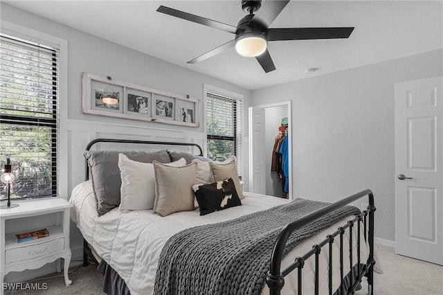 bedroom with a ceiling fan, a spacious closet, and light colored carpet