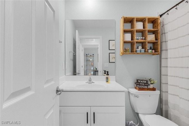 bathroom featuring toilet, vanity, and a shower with curtain