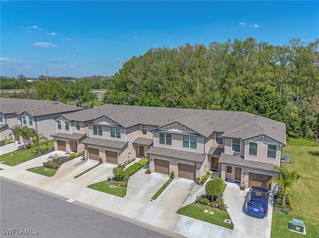 townhome / multi-family property featuring an attached garage, a residential view, driveway, and a shingled roof