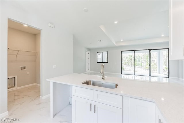 kitchen featuring baseboards, light stone countertops, marble finish floor, white cabinetry, and a sink