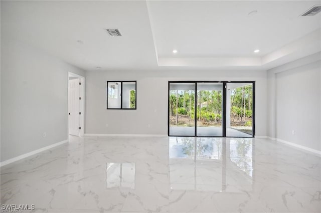 empty room featuring a tray ceiling, marble finish floor, visible vents, and baseboards