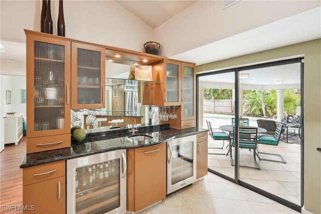 kitchen featuring dark stone counters, beverage cooler, a sink, and light tile patterned floors