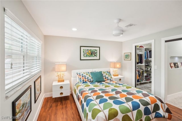 bedroom featuring baseboards, visible vents, wood finished floors, a spacious closet, and a closet