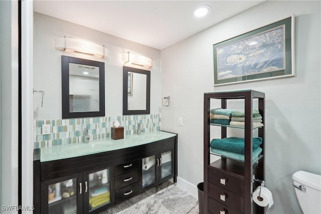 bathroom featuring double vanity, tasteful backsplash, a sink, and toilet