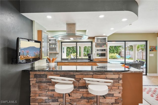 bar featuring tasteful backsplash, recessed lighting, a sink, island range hood, and oven