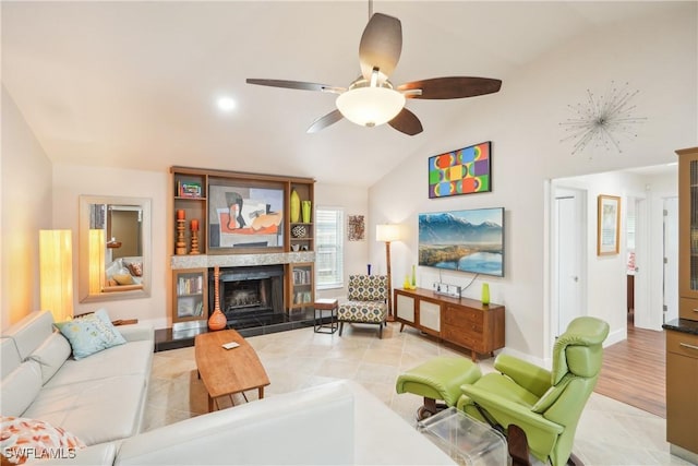 living room with a ceiling fan, lofted ceiling, a fireplace with raised hearth, and baseboards