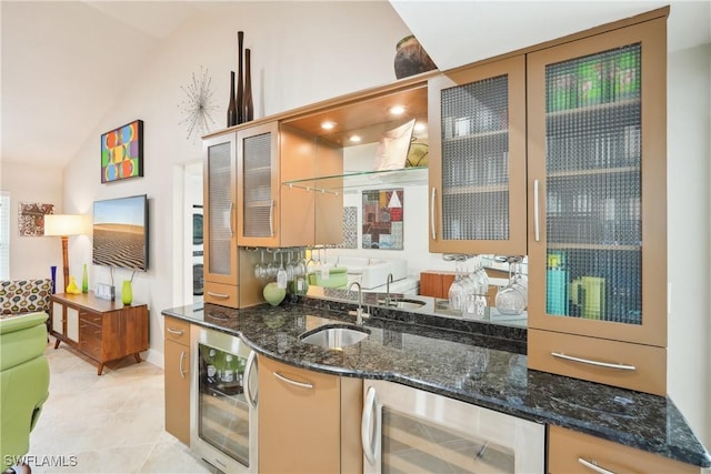 kitchen featuring lofted ceiling, wine cooler, dark stone counters, and a sink