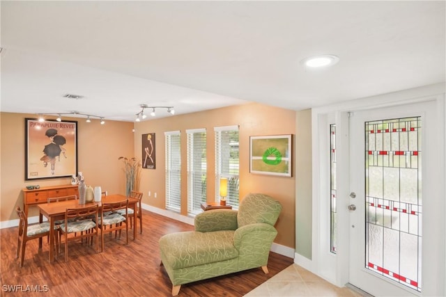 dining area with baseboards, track lighting, visible vents, and wood finished floors