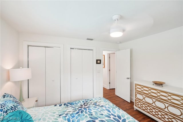 bedroom featuring visible vents, dark wood finished floors, and two closets