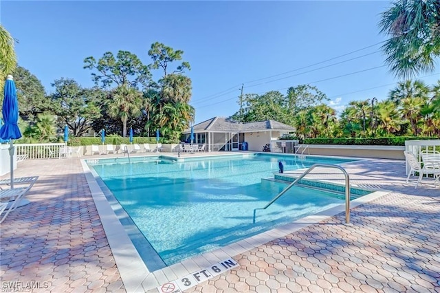 community pool with fence, an outbuilding, and a patio