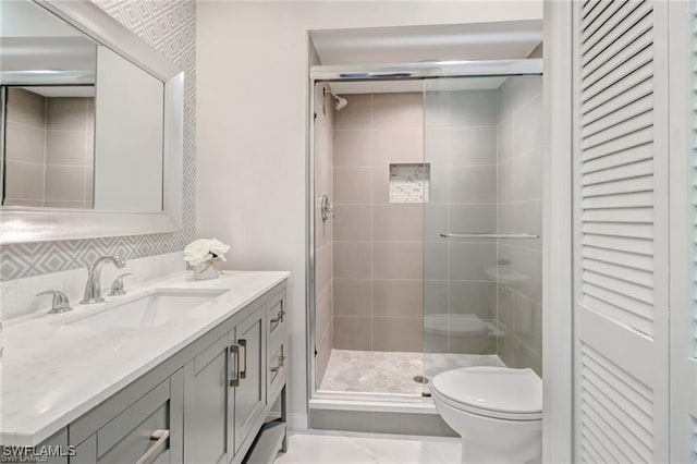 bathroom with a shower stall, toilet, and vanity