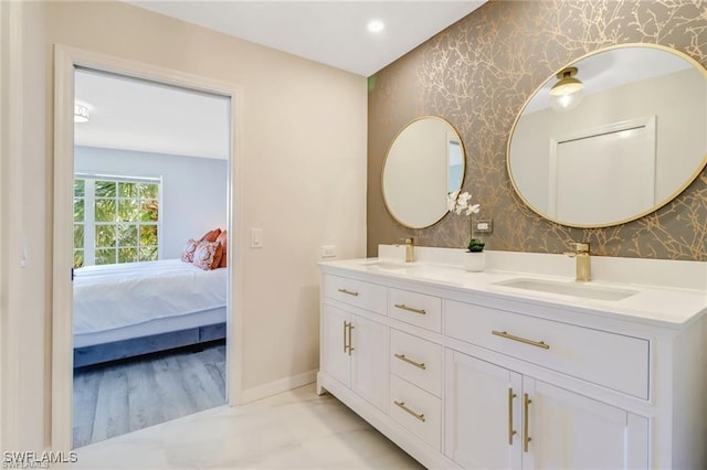 bathroom with baseboards, a sink, ensuite bathroom, and wallpapered walls