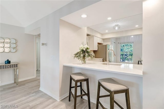 kitchen with light wood-style flooring, recessed lighting, a peninsula, and a kitchen bar