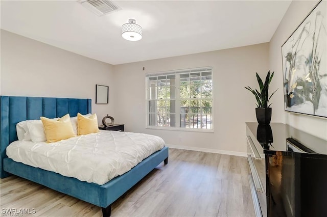 bedroom with visible vents, baseboards, and wood finished floors