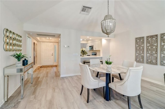 dining space featuring light wood-style floors, baseboards, visible vents, and a chandelier