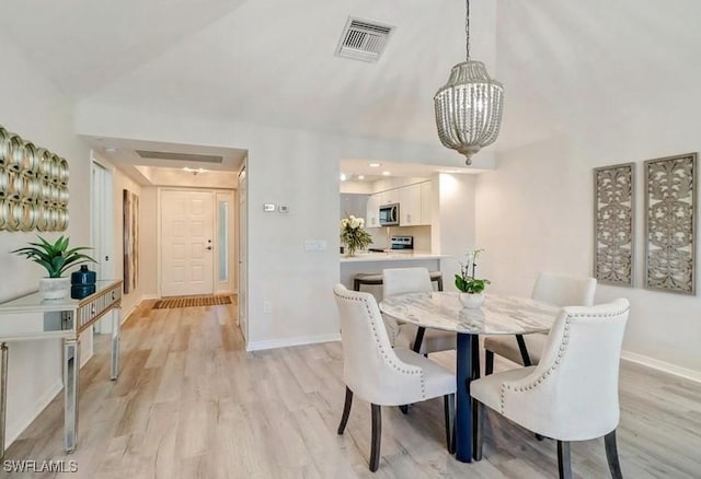 dining space with visible vents, baseboards, an inviting chandelier, vaulted ceiling, and light wood-style floors