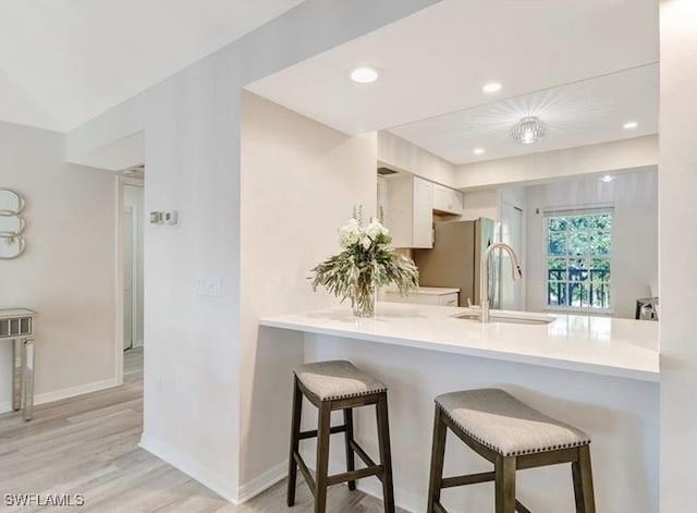 kitchen with a sink, a peninsula, a breakfast bar area, and freestanding refrigerator