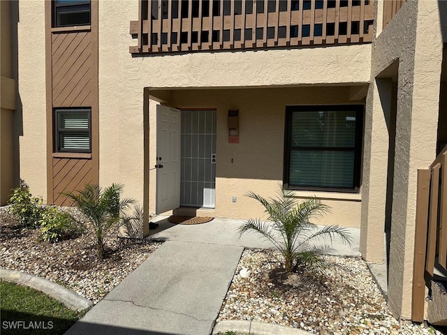 entrance to property with a balcony and stucco siding