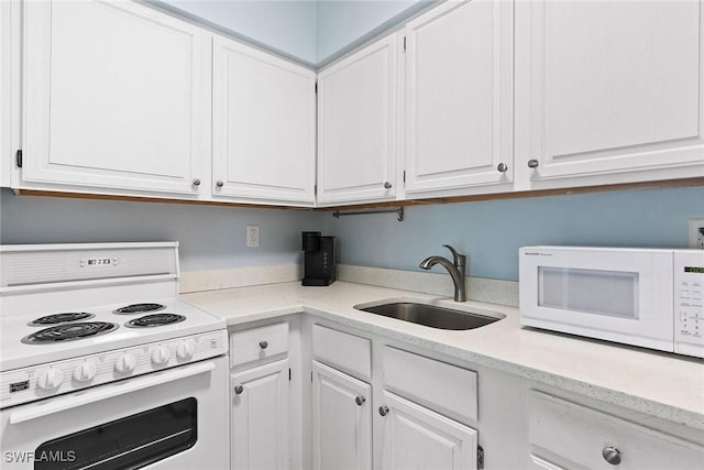 kitchen featuring light stone counters, white appliances, a sink, and white cabinetry