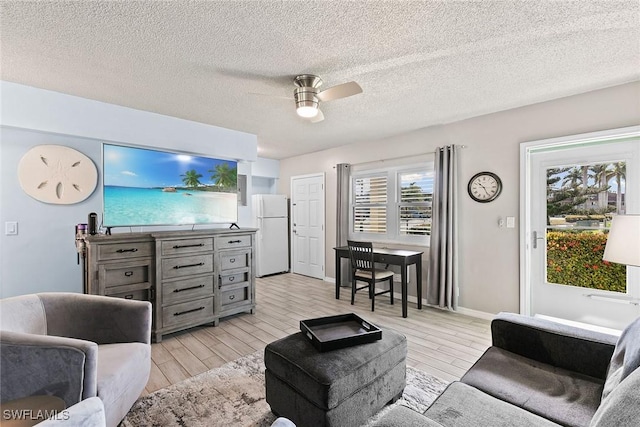 living area with ceiling fan, wood finish floors, a textured ceiling, and baseboards