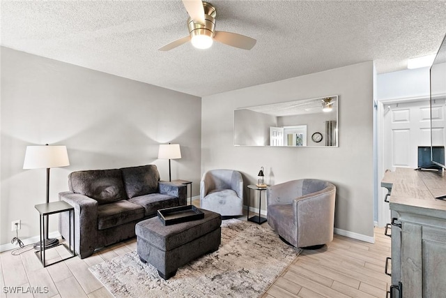 living room with light wood-style flooring, baseboards, ceiling fan, and a textured ceiling