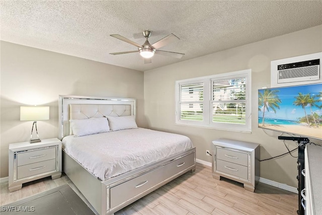 bedroom with wood tiled floor, a textured ceiling, baseboards, and an AC wall unit