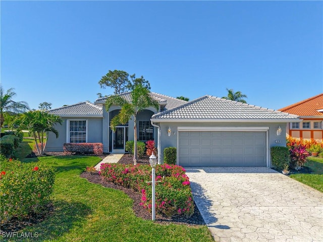 view of front of house featuring stucco siding, a tiled roof, an attached garage, and a front lawn