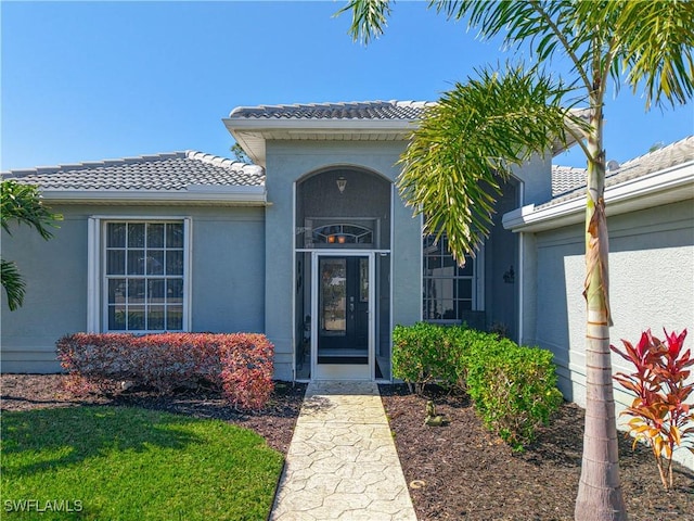 view of exterior entry featuring a tile roof and stucco siding