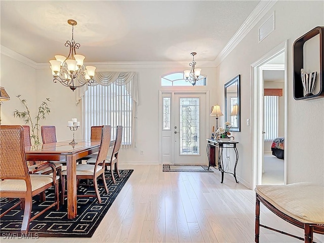 dining space featuring a notable chandelier, visible vents, light wood finished floors, and ornamental molding