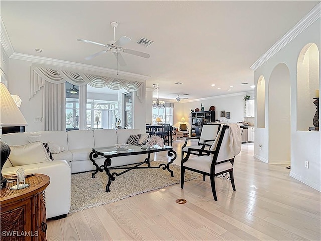 living room featuring visible vents, arched walkways, light wood-style floors, and ornamental molding