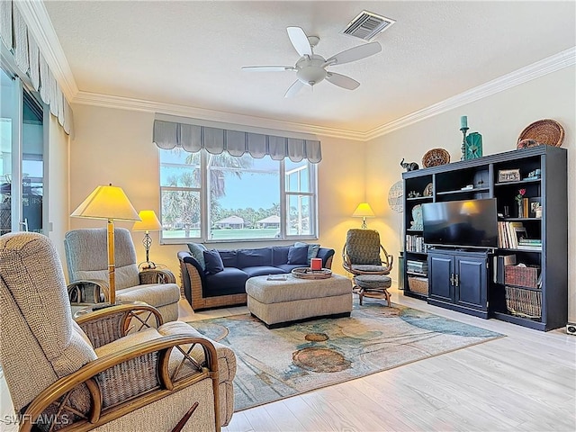 living room with visible vents, crown molding, a ceiling fan, and wood finished floors