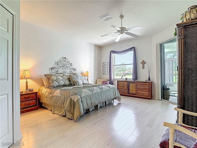 bedroom with visible vents, light wood-type flooring, a textured ceiling, a ceiling fan, and access to outside