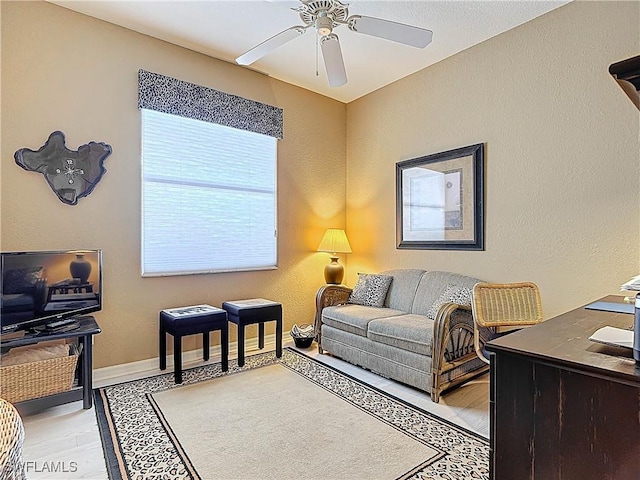 office space with baseboards, light wood-style flooring, and a ceiling fan