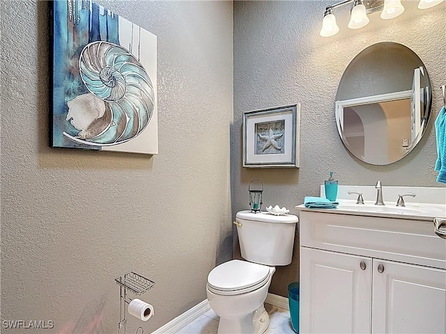 half bath with vanity, toilet, a textured wall, and baseboards