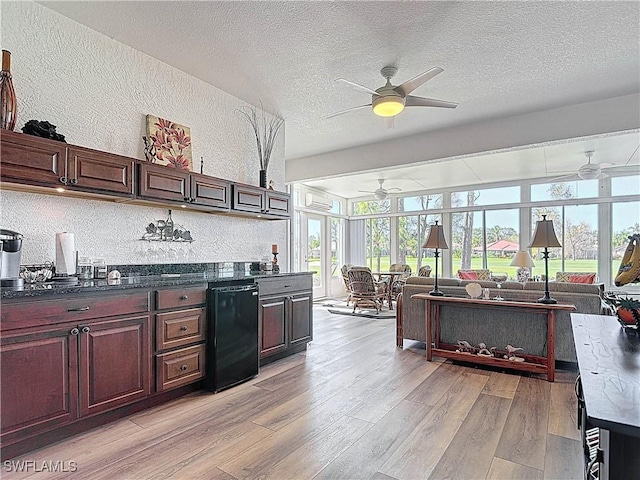 kitchen with light wood-style flooring, a textured ceiling, dishwasher, dark countertops, and open floor plan