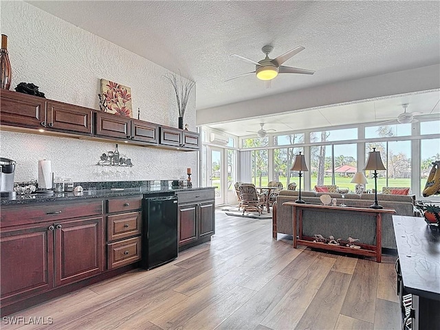 3519 Barnstable Ct, North Fort Myers, FL 33917 - kitchen with ceiling fan, a textured wall, a textured ceiling, light wood-style flooring, and dark countertops