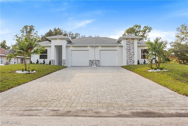 prairie-style home featuring a garage, a front lawn, decorative driveway, and stucco siding