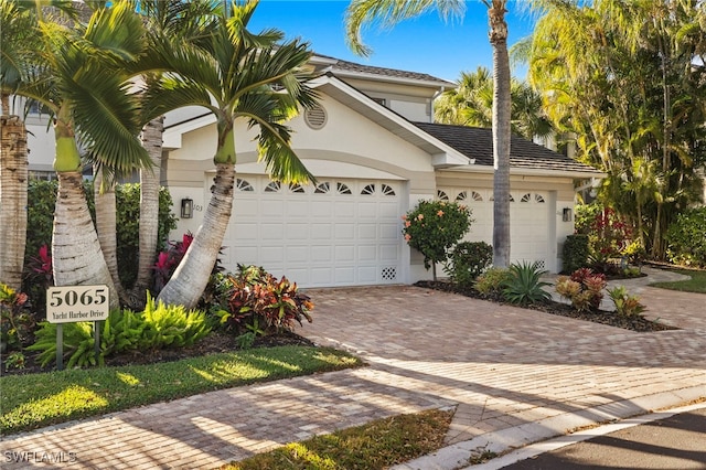 view of front facade featuring a garage, decorative driveway, and stucco siding